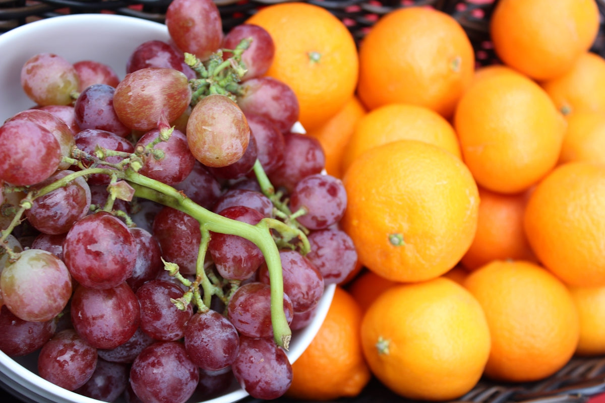 orange fruits and green leaves on blue plastic basket