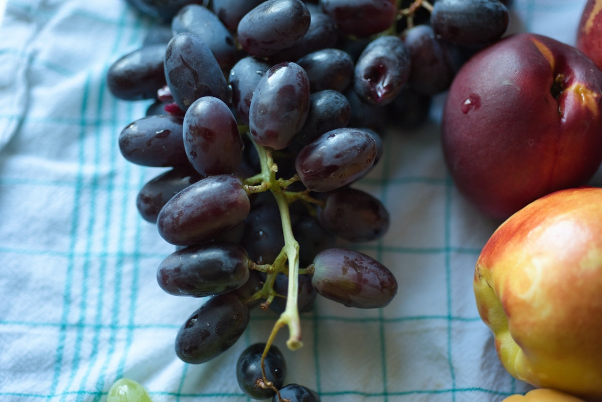 Grapes and other fruits on a checkered cloth.